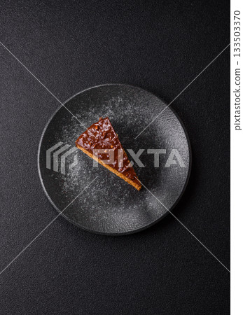 A slice of sweet layered cake covered in chocolate with nuts and caramel. A slice of chocolate cake A slice of sweet layered cake covered in chocolate with nuts and caramel. A slice of chocolate cake 133503370