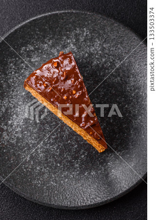 A slice of sweet layered cake covered in chocolate with nuts and caramel. A slice of chocolate cake A slice of sweet layered cake covered in chocolate with nuts and caramel. A slice of chocolate cake 133503374