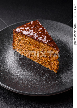 A slice of sweet layered cake covered in chocolate with nuts and caramel. A slice of chocolate cake A slice of sweet layered cake covered in chocolate with nuts and caramel. A slice of chocolate cake 133503375