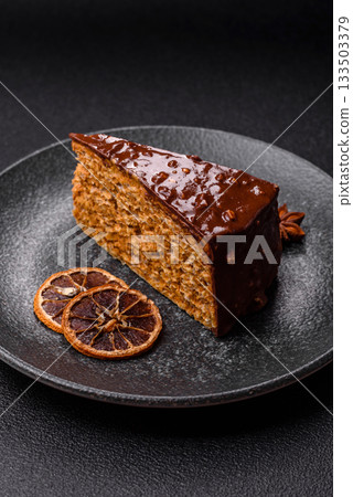 A slice of sweet layered cake covered in chocolate with nuts and caramel. A slice of chocolate cake A slice of sweet layered cake covered in chocolate with nuts and caramel. A slice of chocolate cake 133503379