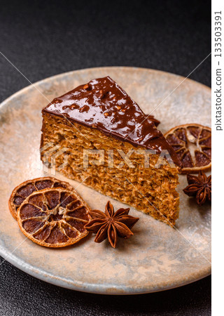 A slice of sweet layered cake covered in chocolate with nuts and caramel. A slice of chocolate cake 133503391