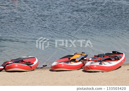 Three SUP boards on a sandy beach near the water Three SUP boards on a sandy beach near the water 133503420