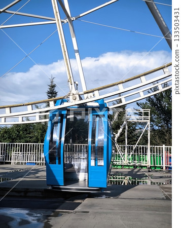 A blue cabin of a modern Ferris wheel against a blue sky A blue cabin of a modern Ferris wheel against a blue sky 133503431