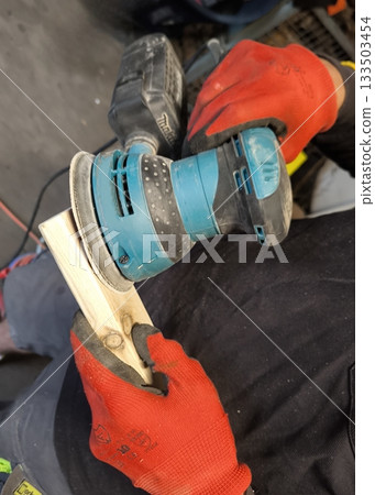 Hands in gloves sanding a wooden board 133503454