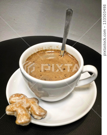 Hot chocolate or coffee or cocoa in a white cup with gingerbread on a black background Hot chocolate or coffee or cocoa in a white cup with gingerbread on a black background 133503498