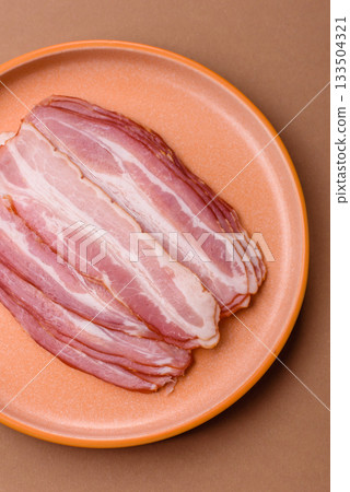 Meat, raw pork bacon sliced, organic food, protein for snacks. Raw bacon as a background Meat, raw pork bacon sliced, organic food, protein for snacks. Raw bacon as a background 133504321