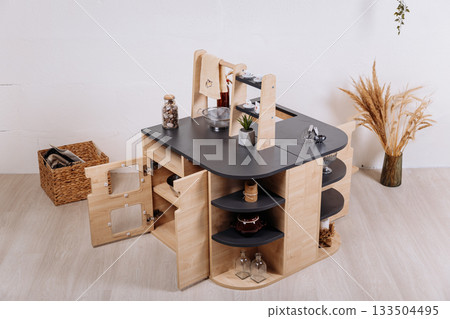 Wooden kids play kitchen island with shelves in minimalist nursery interior Wooden kids play kitchen island with shelves in minimalist nursery interior 133504495