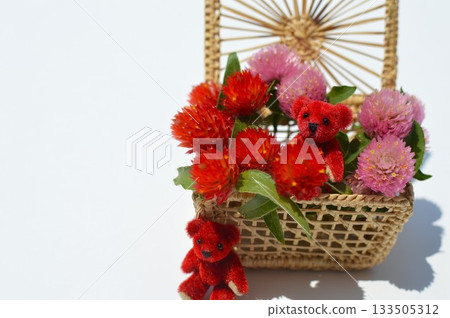A basket of celosia flowers and a small teddy bear 133505312