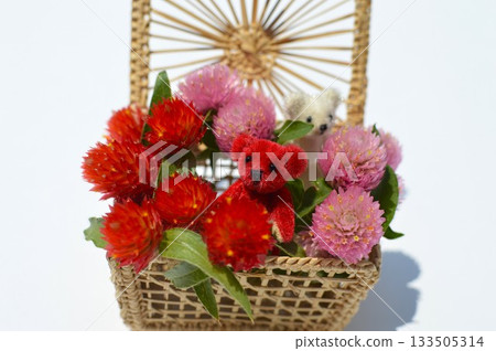 A basket of celosia flowers and a small teddy bear 133505314