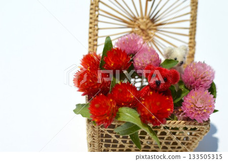 A basket of celosia flowers and a small teddy bear 133505315