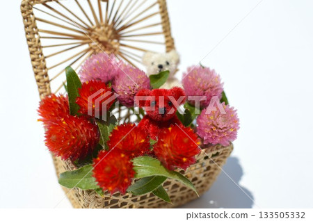 A basket of celosia flowers and a small teddy bear 133505332