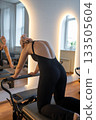 Woman with dreadlocks determined woman in black leggings performs pilates with focused energy 133505604