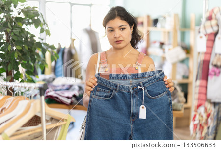 Latina chooses jeans in a clothing store Latina chooses jeans in a clothing store 133506633