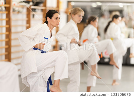 Women practice fighting stances during karate 133506676