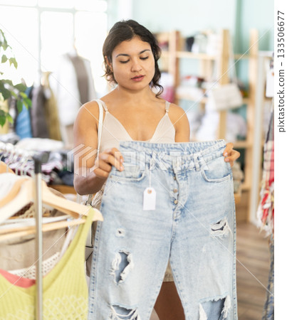 Young woman choosing jeans in clothing store Young woman choosing jeans in clothing store 133506677