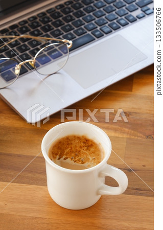 電腦和咖啡－一張在辦公桌前用筆記型電腦工作，同時喝著新鮮沖泡咖啡的圖片。 133506766