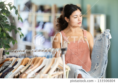 Young woman choosing jeans in clothing store Young woman choosing jeans in clothing store 133506804