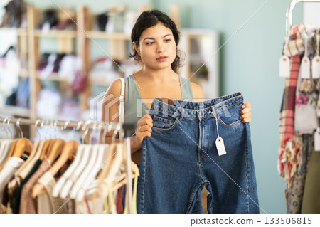 Undetermined young girl choosing jeans pantaloons in clothing store 133506815