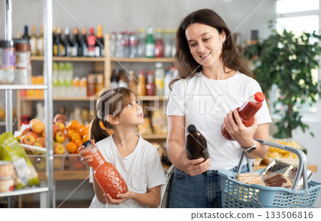 Child girl with mother choose consider juice Child girl with mother choose consider juice 133506816