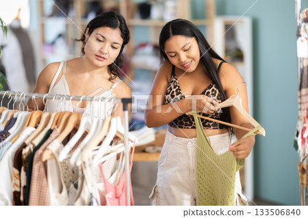 Two girlfriends chooses dresses or o tops for the summer period in fashionable clothing store 133506840