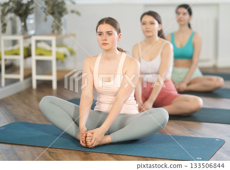 Young girl performing butterfly pose at group yoga session Young girl performing butterfly pose at group yoga session 133506844