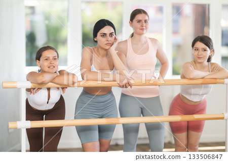 Young female ballet students relaxing at barre in studio Young female ballet students relaxing at barre in studio 133506847