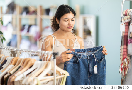 Girl at trading floor pick out and buying jeans trousers Girl at trading floor pick out and buying jeans trousers 133506900