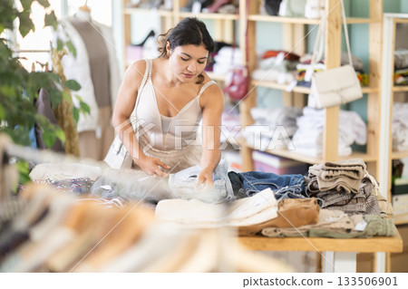 Young woman choosing trousers in clothing store 133506901
