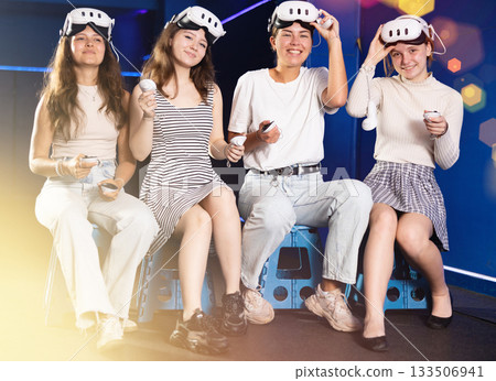 Portrait of happy four girlfriends wearing virtual reality glasses together in dark room Portrait of happy four girlfriends wearing virtual reality glasses together in dark room 133506941