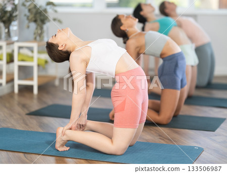 Young girl performing camel pose during group yoga session Young girl performing camel pose during group yoga session 133506987