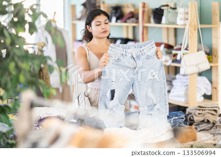 Undetermined young girl choosing jeans pantaloons in clothing store 133506994