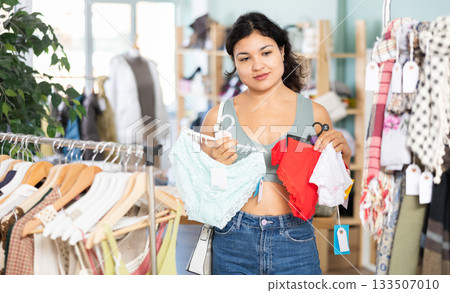 Young woman chooses panties in clothing store Young woman chooses panties in clothing store 133507010
