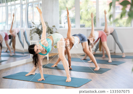Women meditates in yoga pose parshvottanasana in gym Women meditates in yoga pose parshvottanasana in gym 133507075