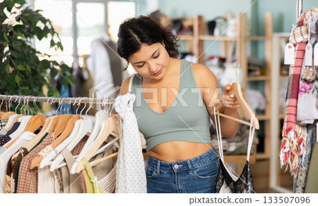 Young woman chooses dresses and tops in store 133507096