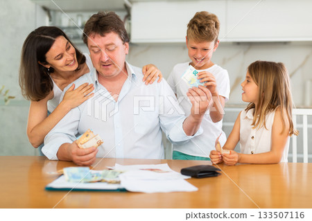 Head of family gives his wife and children pocket money Head of family gives his wife and children pocket money 133507116