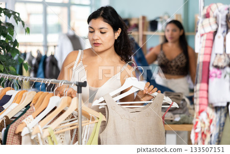 Young woman chooses dresses and tops in store 133507151
