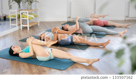 Young girl performing Eka Pada Apanasana in yoga studio Young girl performing Eka Pada Apanasana in yoga studio 133507162