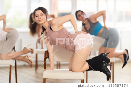 Slender women rehearse modern dances using chair 133507174