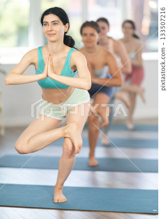 Fitness, sport and healthy lifestyle concept: woman doing yoga yoga pose - vrikshasana pose 133507216