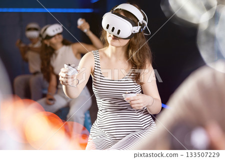 Expressive girl in VR goggles having fun in virtual reality room 133507229