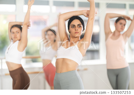 Young brunette participating in beginner group ballet class Young brunette participating in beginner group ballet class 133507253