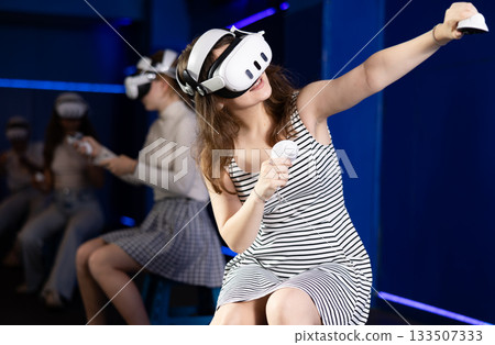 Expressive girl in VR goggles having fun in virtual reality room 133507333