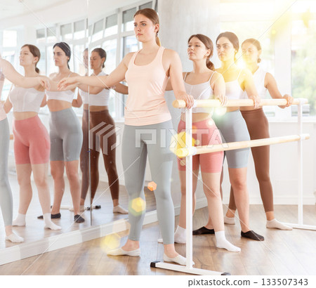 Young girl practicing second position holding by ballet barre 133507343