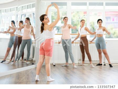 Young female ballet student performing solo during group practice Young female ballet student performing solo during group practice 133507347