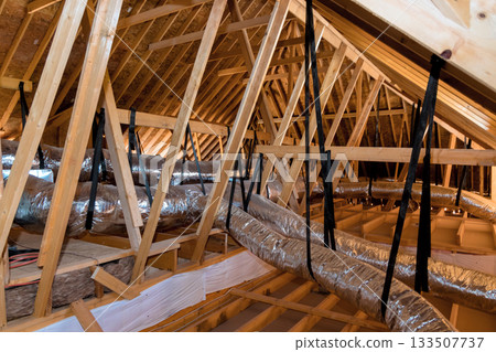 Workers are checking attic ductwork roof framing for proper installation ventilation during renovations. 133507737