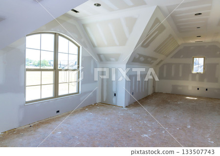 Bright room in modern home features large windows bare drywall, awaiting finishing touches decor. 133507743