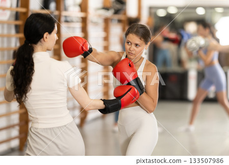 Young girl training boxing with partner during sports classes Young girl training boxing with partner during sports classes 133507986