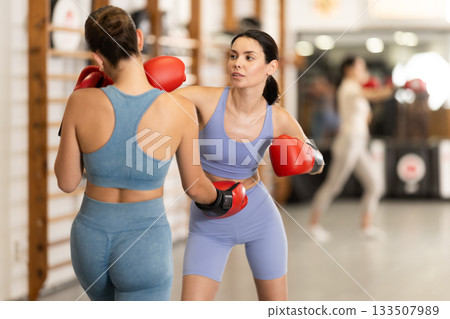 Young girl training boxing with partner during sports classes 133507989