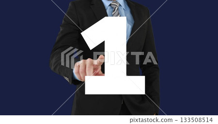 Pointing businessman wearing black suit and striped tie in studio, with white numeral 1 overlay 133508514