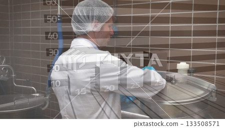 Lifting vat lid, technician wearing lab coat and hairnet inspecting vat in plant, with tiled wall 133508571